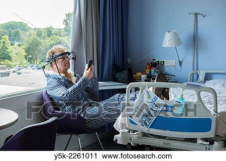 "Tilburg, Netherlands. Male patient with fractured cervical reading messages on his phone while sitting in a chair in his hospital room. " View Large Photo Image Stock Image - "Tilburg, Netherlands. Male patient with fractured cervical reading messages on his phone while sitting in a chair in his hospital room. ". Fotosearch