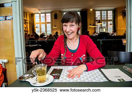 "Tilburg, Netherlands. Portrait of a 61 year old colorful dressed and fashionable woman preparing for lunch in a daytime cafe-restaurant. " View Large Photo Image Stock Photography - "Tilburg, Netherlands. Portrait of a 61 year old colorful dressed and fashionable woman preparing for lunch in a daytime cafe-restaurant. ". Fotosearch