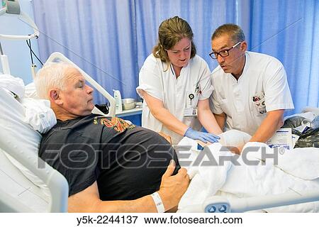 "Tilburg, Netherlands. Two colleague nurses refreshing the post operative bandages of a male orthopedics patient after receiving a knee prosthesis. " View Large Photo Image Stock Photo - "Tilburg, Netherlands. Two colleague nurses refreshing the post operative bandages of a male orthopedics patient after receiving a knee prosthesis. ". Fotosearch