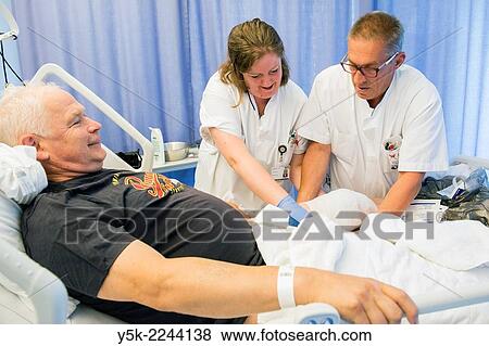 "Tilburg, Netherlands. Two colleague nurses refreshing the post operative bandages of a male orthopedics patient after receiving a knee prosthesis. " View Large Photo Image Stock Photo - "Tilburg, Netherlands. Two colleague nurses refreshing the post operative bandages of a male orthopedics patient after receiving a knee prosthesis. ". Fotosearch