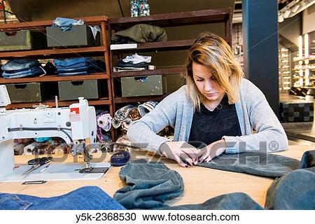 "Tilburg, Netherlands. Young needlewoman buzzy shortening a jeans at her workstation in a fashion store for one of her customers. " View Large Photo Image Stock Image - "Tilburg, Netherlands. Young needlewoman buzzy shortening a jeans at her workstation in a fashion store for one of her customers. ". Fotosearch