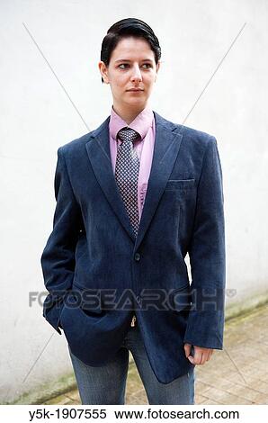 Stock Photography - "Tilburg, Netherlands. Young woman, dressed up as a man, standing in front of a concrete wall near main street. ". Fotosearch