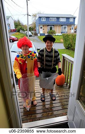 Stock Photography - Two boys dressed in halloween costumes on the doorstep of a home waoting for treats or candy.. Fotosearch