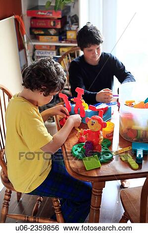 Two young boys playing with toys on a table View Large Photo Image Stock Photograph - Two young boys playing with toys on a table. Fotosearch