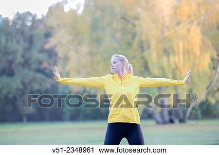 Stock Image - Young blonde woman doing gymnastics in park. Fotosearch