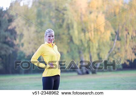 Stock Image - Young blonde woman doing gymnastics in park. Fotosearch
