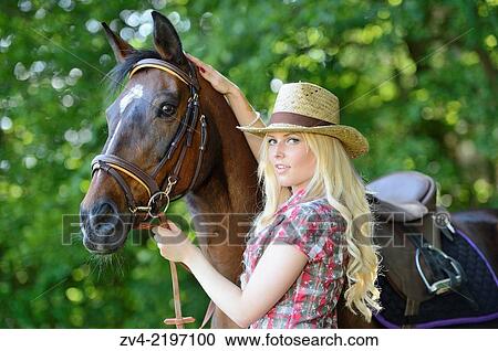 Stock Image - Young cowgirl standing beside a polish arabian horse.. Fotosearch