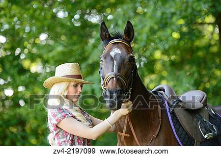 Stock Photo - Young cowgirl standing beside a polish arabian horse.. Fotosearch