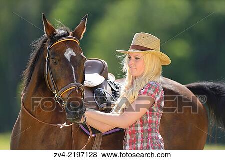 Stock Photo - Young cowgirl standing beside a polish arabian horse.. Fotosearch