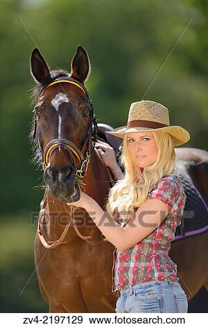 Stock Photo - Young cowgirl standing beside a polish arabian horse.. Fotosearch