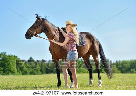 Young cowgirl with a polish arabian horse standing on a meadow. View Large Photo Image Stock Photo - Young cowgirl with a polish arabian horse standing on a meadow.. Fotosearch