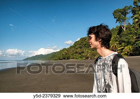 Stock Photo - "young male European traveller on empty beach, wild coast of the Pacific Ocean, Corcovado National Park, Costa Rica,.". Fotosearch