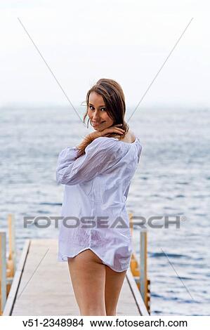 Picture - Young pretty woman walking untill the end of a pier and smiling at camera. Fotosearch
