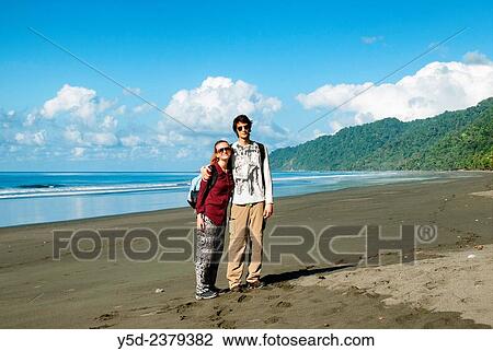 Stock Image - "young travellers on empty beach, wild coast of the Pacific Ocean, Corcovado National Park, Costa Rica,.". Fotosearch