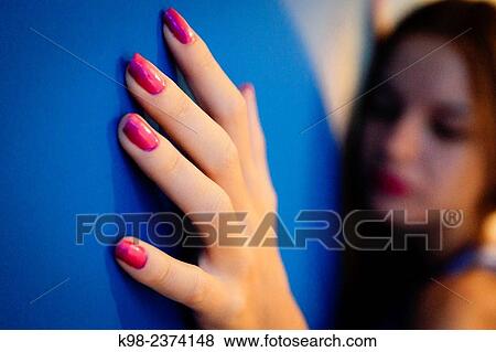 Stock Photo - Young woman leaning on blue wall. Fotosearch