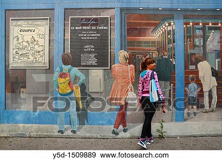 Stock Photo - "young woman pretending walking in to cinema that is painted on the wall as a mural, Lyon, France, Europe". Fotosearch