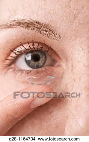 Picture - young woman puttig in her contact lenses ( detail). Fotosearch