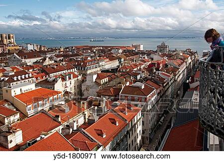 Stock Image - "young woman watching the panorama of old town of Lisbon from top point of elevator de Santa Justa, Lisbon, Portugal, Europe". Fotosearch