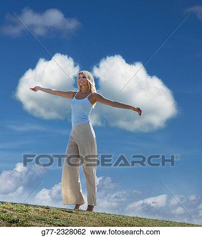 Stock Image - "Young woman with open arms against clouds in the sky, Miami Beach, Florida, USA". Fotosearch