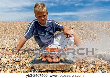 "A Boy Cooks Sausages On The Beach, Seaford, Sussex, UK. " View Large Photo Image Stock Image - "A Boy Cooks Sausages On The Beach, Seaford, Sussex, UK. ". Fotosearch