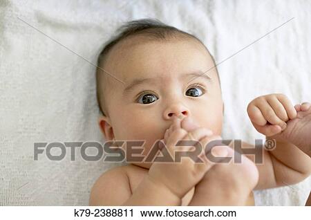 A little baby girl playing with her feet. View Large Photo Image Stock Image - A little baby girl playing with her feet.. Fotosearch