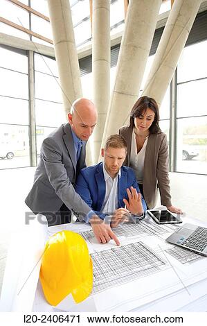 Stock Image - Architects looking at blueprints. Fotosearch