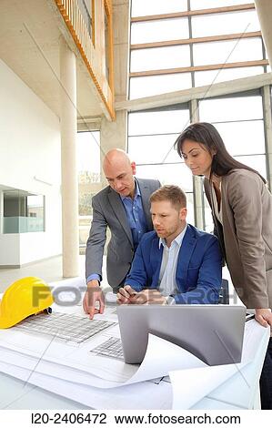Stock Image - Architects looking at blueprints. Fotosearch
