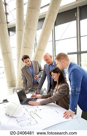 Stock Image - Architects looking at blueprints. Fotosearch