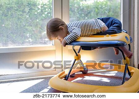 Picture - "Baby, 10 Months, Walker, Leaning, Mischievous, Risk, Indoors, Door- window, sunlight, garden, Playful". Fotosearch