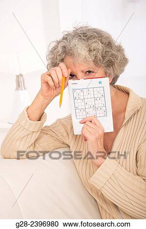 "Beautiful senior woman, doing a sudoku game with a pen in her hans and a sudoku magazine, at home" View Large Photo Image Stock Image - "Beautiful senior woman, doing a sudoku game with a pen in her hans and a sudoku magazine, at home". Fotosearch