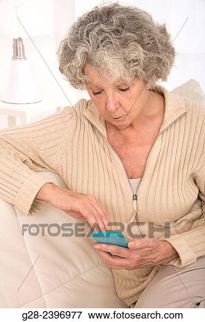 "Beautiful senior woman writing and reading a message on her mobile-phone, at home" View Large Photo Image Stock Photo - "Beautiful senior woman writing and reading a message on her mobile-phone, at home". Fotosearch