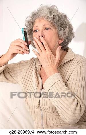 Beautiful surprised senior woman on the phone with hand in front of her mouth View Large Photo Image Picture - Beautiful surprised senior woman on the phone with hand in front of her mouth. Fotosearch