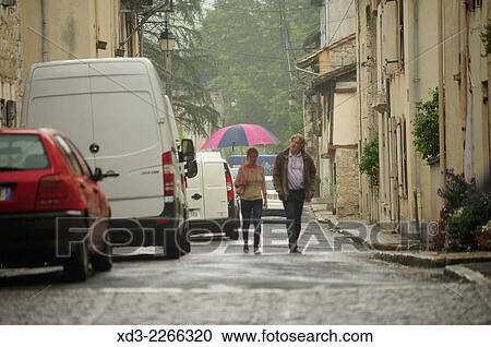 Stock Image - "couple on rainy street, Eymet, Dordogne Department, Aquitaine, France. ". Fotosearch