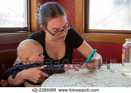 "Denver, Colorado - Seven-month-old Adam Hjermstad Jr. tries to help his mother, Mariel West, with her cell phone. " View Large Photo Image Stock Photo - "Denver, Colorado - Seven-month-old Adam Hjermstad Jr. tries to help his mother, Mariel West, with her cell phone. ". Fotosearch