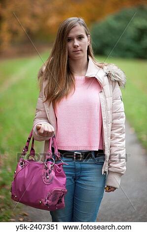 Stock Image - "Driebergen, Netherlands. Young, thoughtful teenager with purple handbag making a stroll through the park. ". Fotosearch