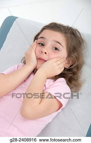 Stock Photograph - Little girl 7 lying on medical couch in surgery room and looking worried. Fotosearch