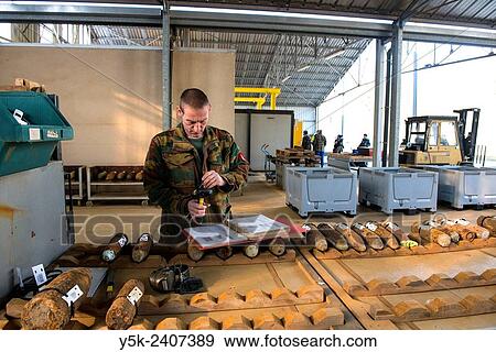 "Poelkapelle, Belgium. Army Battalion for Demolition of Explosives. Army chief corporal working on the identification and classification of recovered live World War 1 shells and munition, prior to demolition. " View Large Photo Image Stock Photo - "Poelkapelle, Belgium. Army Battalion for Demolition of Explosives. Army chief corporal working on the identification and classification of recovered live World War 1 shells and munition, prior to demolition. ". Fotosearch