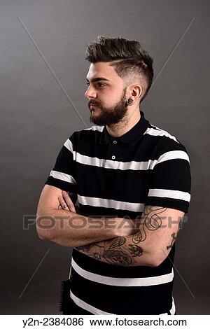 Stock Photograph - Portrait of a male hair stylist with tattoos and piercings.. Fotosearch