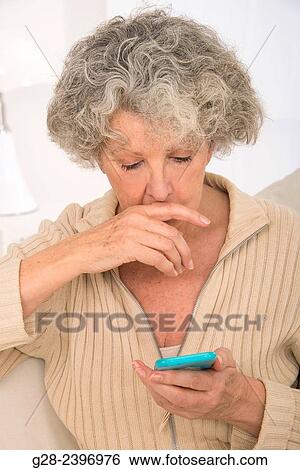 "Puzzled beautiful senior woman writing and reading a message on her mobile-phone, at home" View Large Photo Image Stock Photograph - "Puzzled beautiful senior woman writing and reading a message on her mobile-phone, at home". Fotosearch