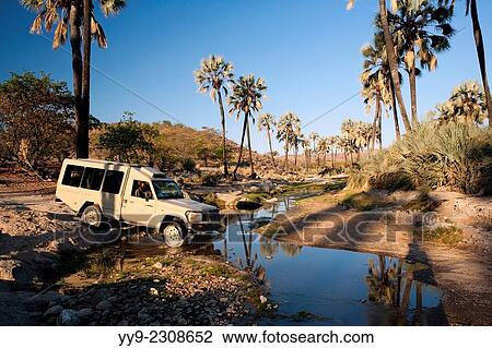 Stock Image - "Safari Vehicle Crossing River - Damaraland - Namibia, Africa. ". Fotosearch