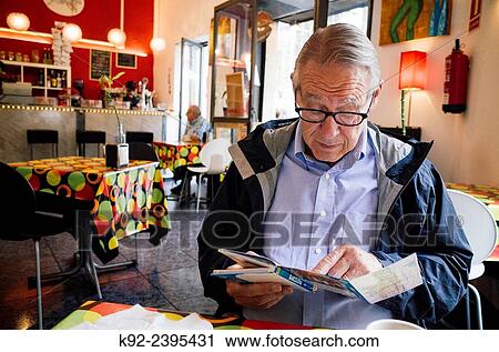 Senior tourist looking at a map in a coffee shop in Barcelona View Large Photo Image Stock Image - Senior tourist looking at a map in a coffee shop in Barcelona. Fotosearch