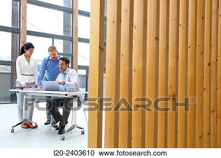 Stock Image - Three executives looking at computer. Fotosearch