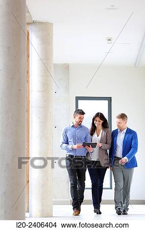 Three executives looking at tablet View Large Photo Image Picture - Three executives looking at tablet. Fotosearch