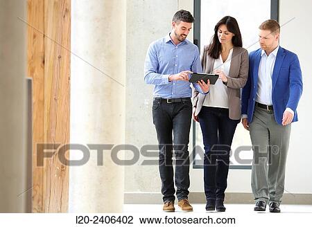 Stock Image - Three executives looking at tablet. Fotosearch