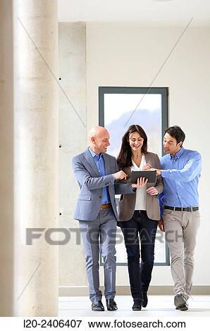Stock Photo - Three executives looking at tablet. Fotosearch