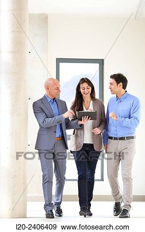 Stock Photo - Three executives looking at tablet. Fotosearch