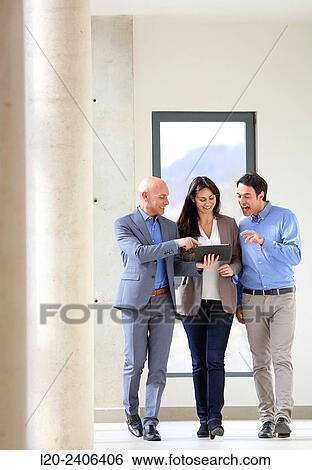 Stock Photograph - Three executives looking at tablet. Fotosearch