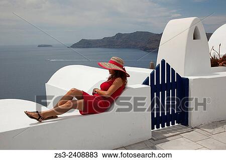 "Woman in red dress sitting near a hotel entrance looking down to Caldera in Oia town, Santorini, Cyclades Islands, Greek Islands, Greece, Europe. " View Large Photo Image Stock Image - "Woman in red dress sitting near a hotel entrance looking down to Caldera in Oia town, Santorini, Cyclades Islands, Greek Islands, Greece, Europe. ". Fotosearch