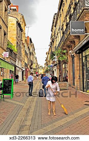 Stock Image - "woman sweeping in front of store, Rue des Ramparts, Bordeaux, Gironde Department, Aquitaine, France. ". Fotosearch
