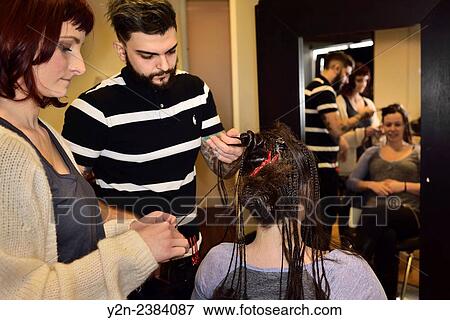 Young male and female trainee hairstylists working on braiding hair of a model in a salon. View Large Photo Image Stock Photo - Young male and female trainee hairstylists working on braiding hair of a model in a salon.. Fotosearch